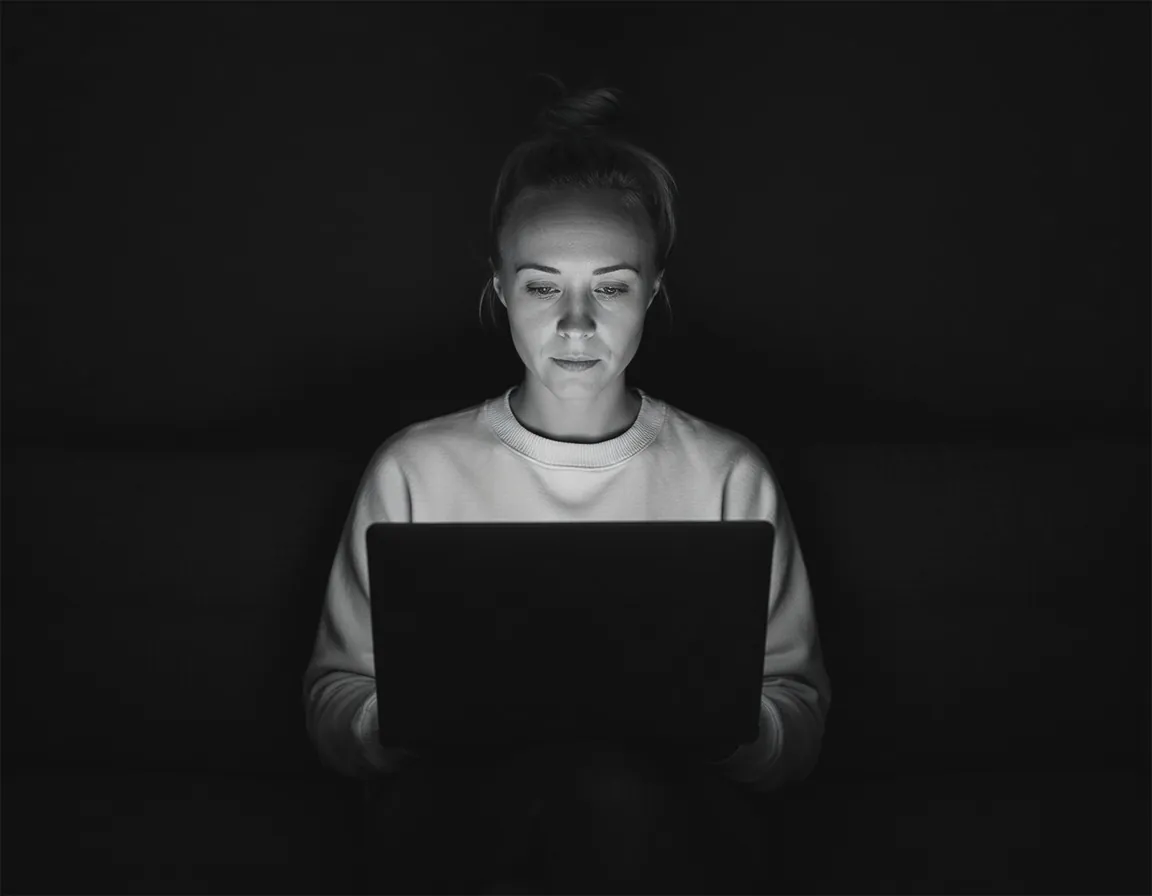 Katie Rutten, who runs Bullfinch projects, schedules and accounts, lit by her laptop screen in a dark room