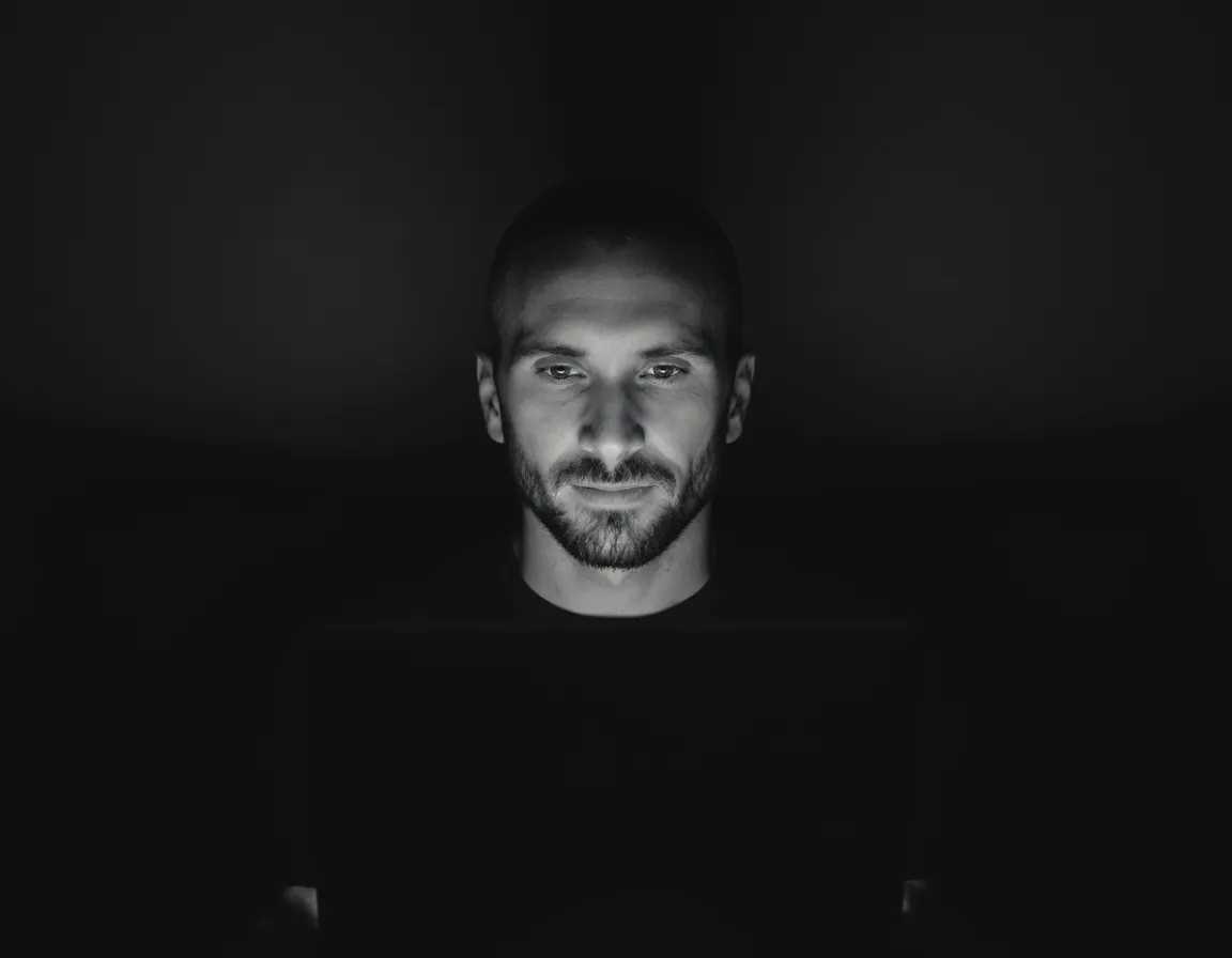 Kyle Rutten, who designs and builds every Bullfinch site, lit by his laptop screen in a dark room