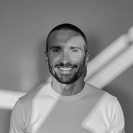 Kyle Rutten, smiling, in a light crew-neck sweater, black and white portrait.