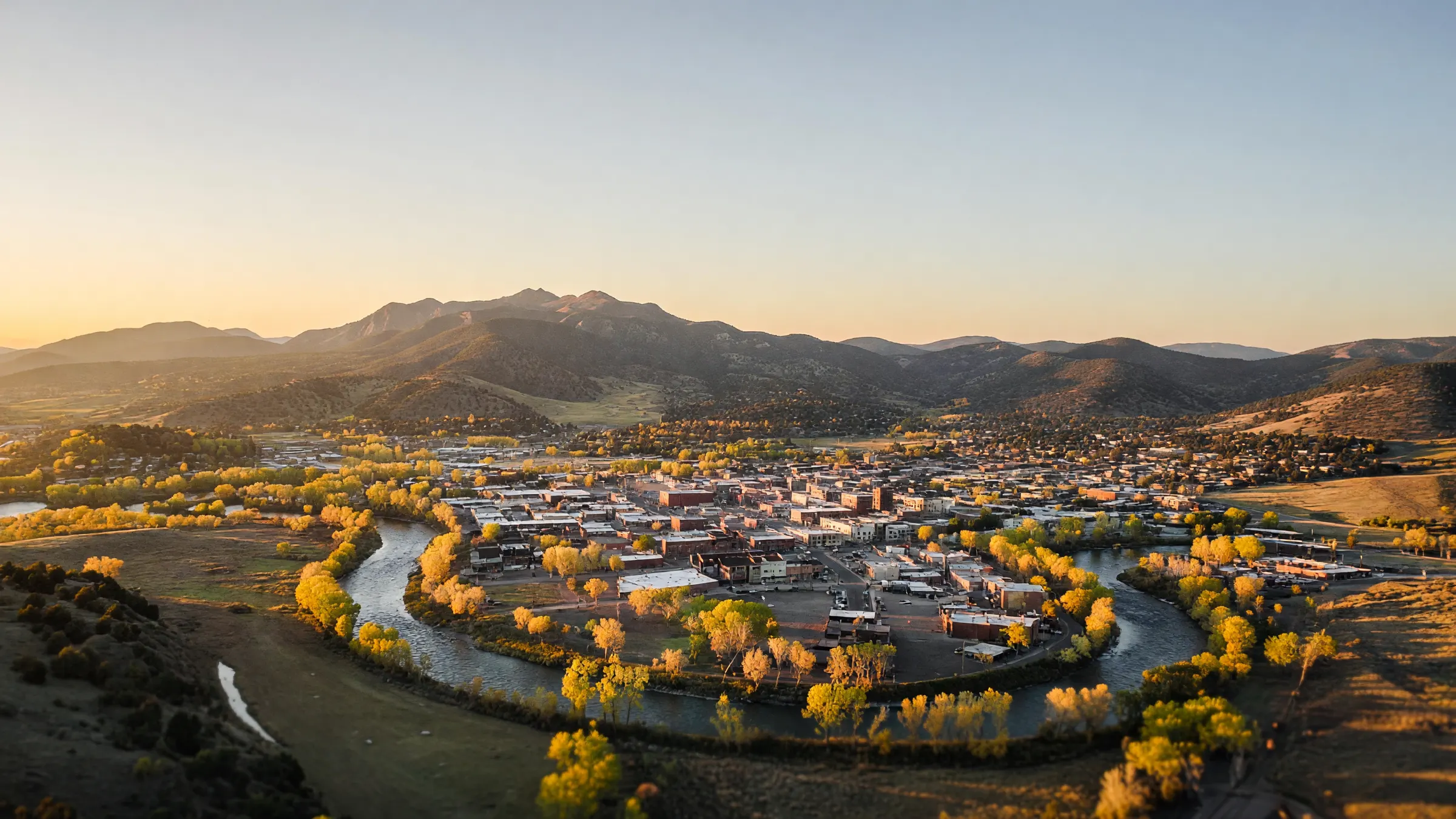 Durango from above at golden hour, the Animas River bending past downtown with the San Juan Mountains behind
