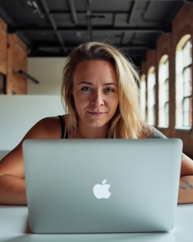 Katie Rutten, who runs operations and the accounts at Bullfinch, smiling over her laptop in a bright brick-walled studio