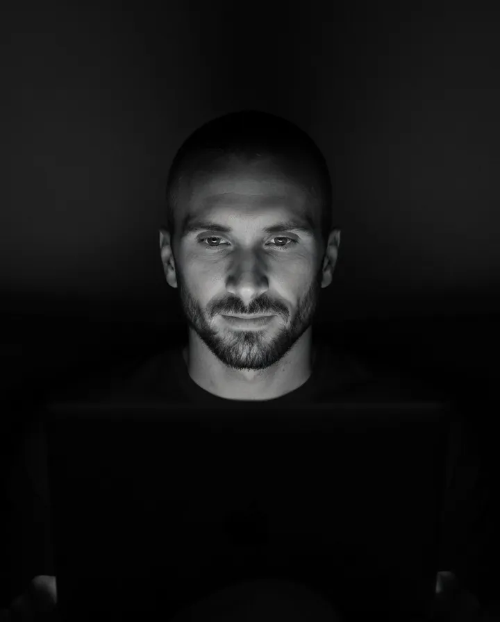 Kyle Rutten, who designs and builds Bullfinch's websites, lit by a laptop screen in a dark room