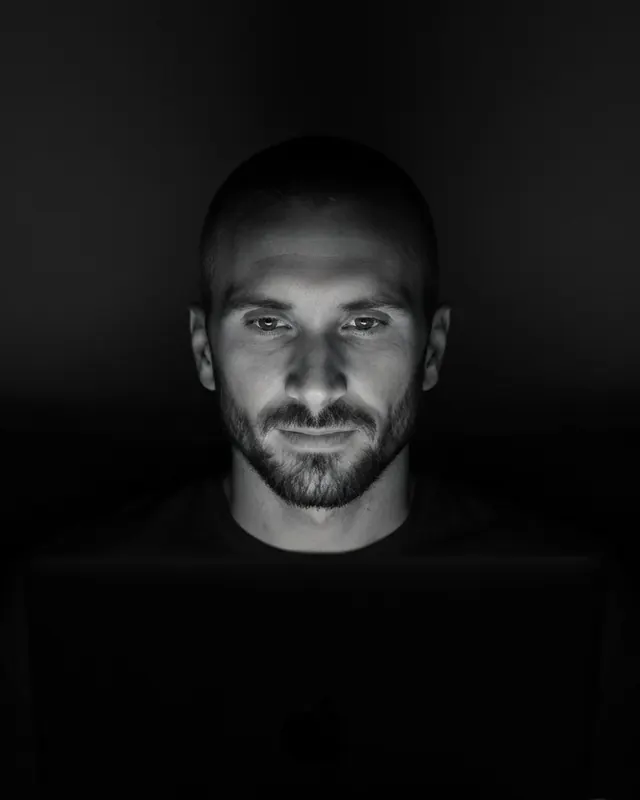 Kyle Rutten, who designs and builds every Bullfinch site, at a laptop in a dark room, his face lit by the screen