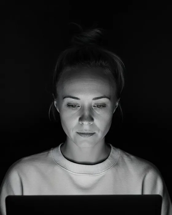 Katie Rutten, who runs each Bullfinch project and account, lit by her laptop screen in a dark room