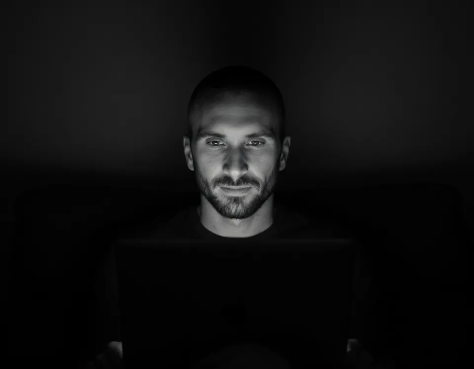 Kyle Rutten of Bullfinch, lit by his laptop screen, in a black and white photo