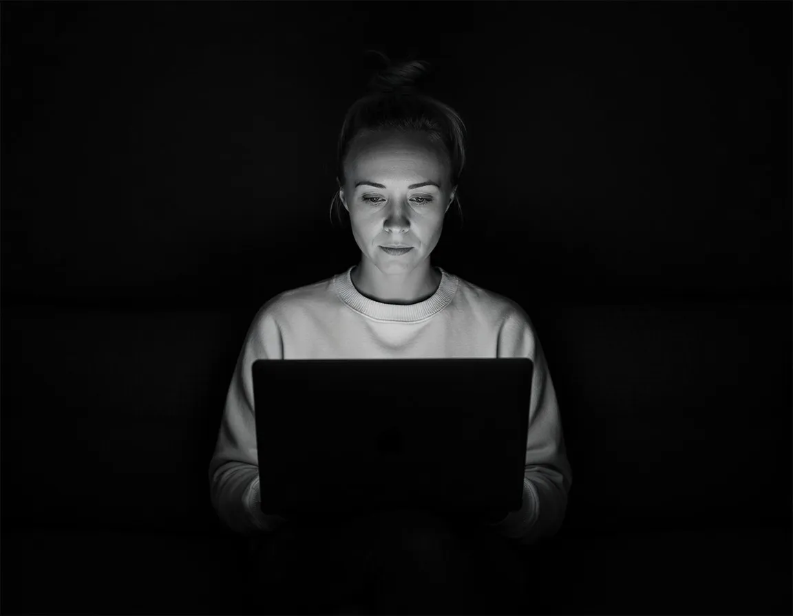 Katie Rutten, Bullfinch's project lead, working at a laptop in a dark room