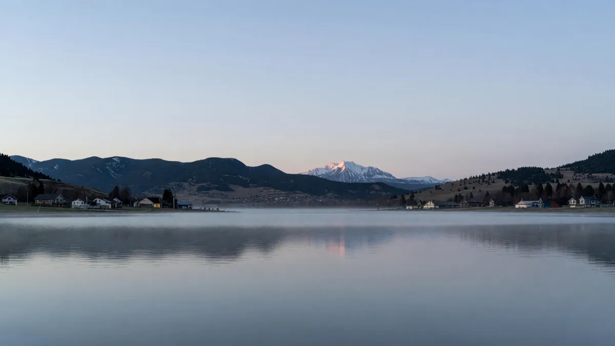 Lake Loveland at dawn: still water, the foothills and snow-capped Longs Peak, homes along the shore