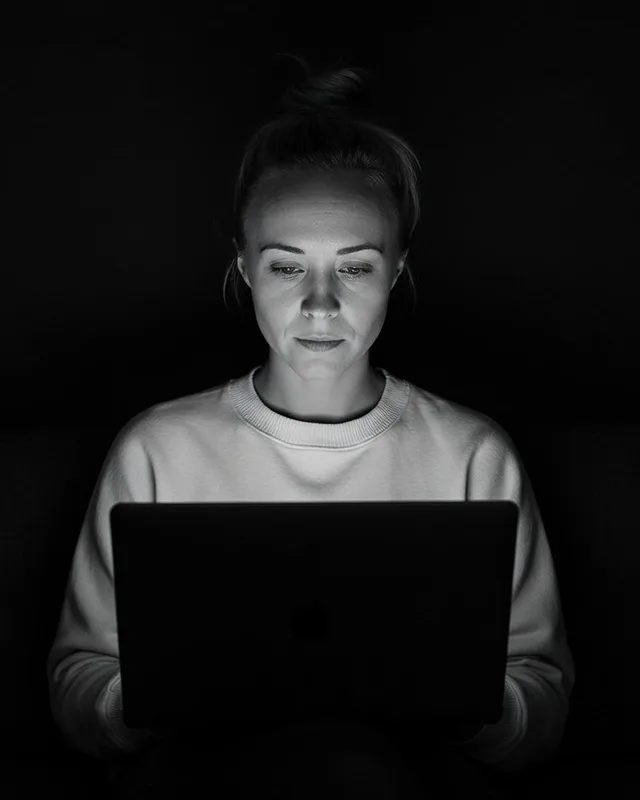 Katie Rutten, who runs Bullfinch projects, working on a laptop in a dark room