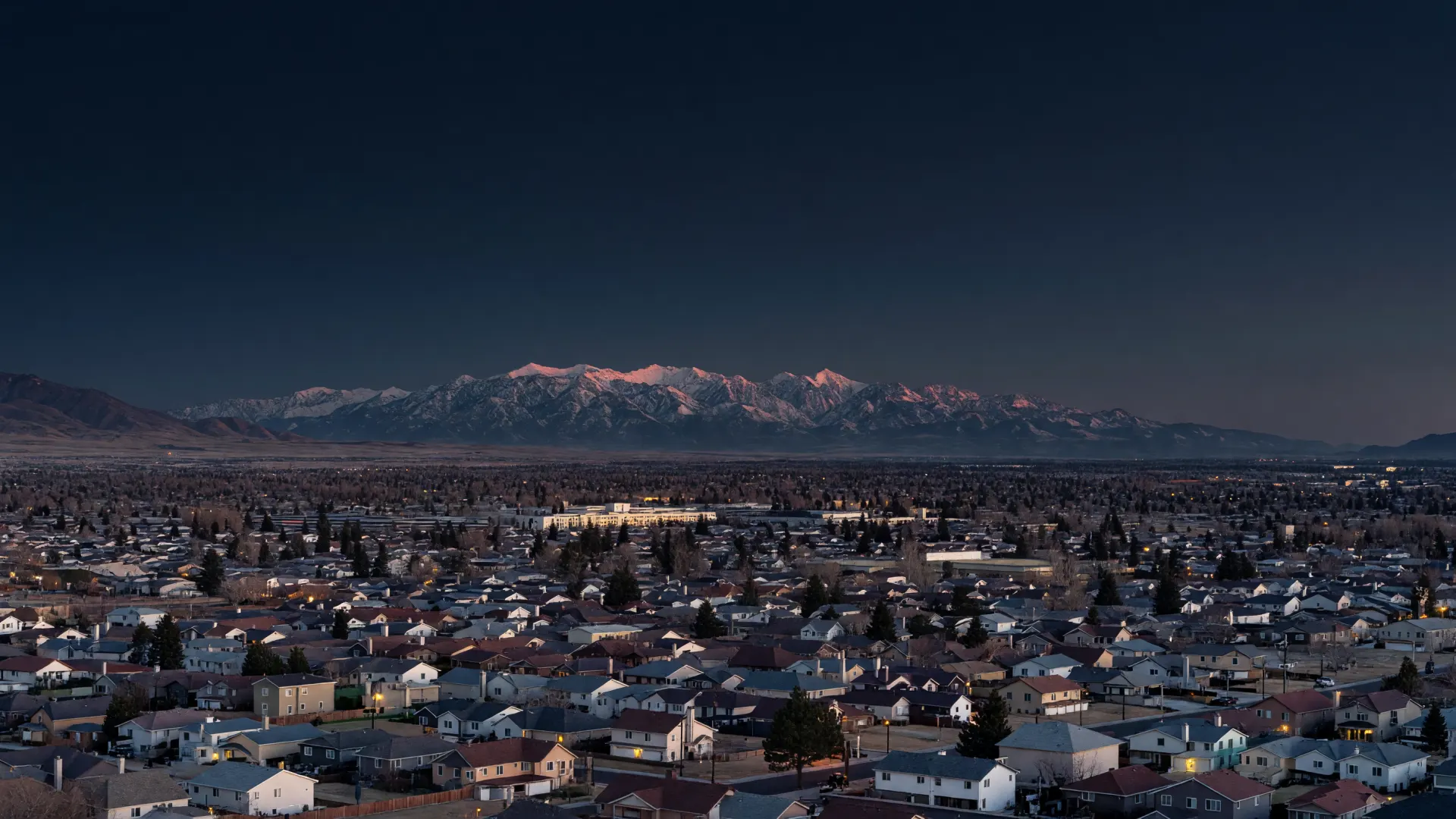 Southwest Salt Lake Valley rooftops and streetlights at dusk, below the Wasatch Range's last light